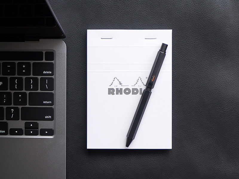 ブラック色ロディアマルチペンがPC・メモ帳と並んでいる様子