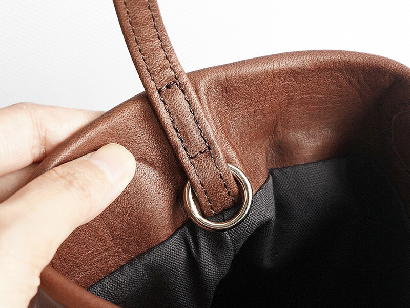 ショルダー紐の片側の付け根には丸カンが付いています。カラビナやキーホルダーなどを付けてお使いいただけます。