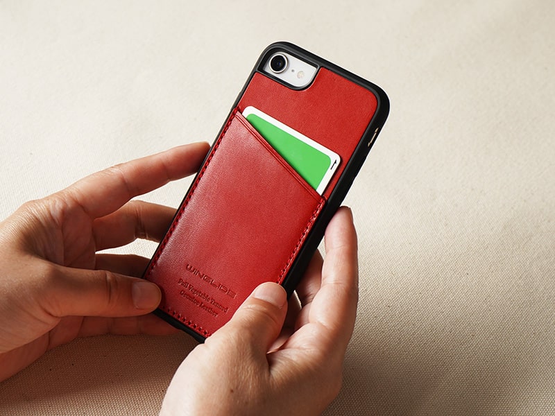 カーキ色のスマホケースを装着したiPhoneを手に持つ画像