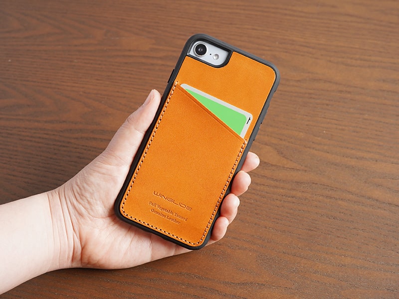 レッド色のスマホケースを装着したiPhoneを手にしている画像