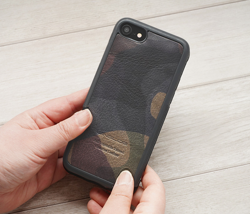 カモフラージュ柄レザー（カーキ）の背面型ケースを手に持った様子